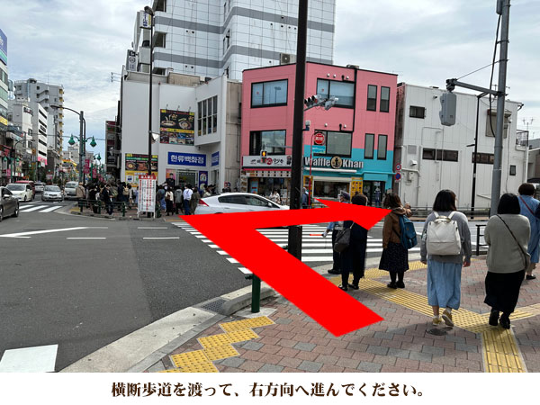 横断歩道を渡って、右方向へ進んでください。