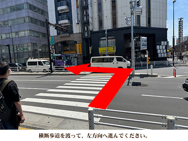 横断歩道を渡って、左方向へ進んでください。